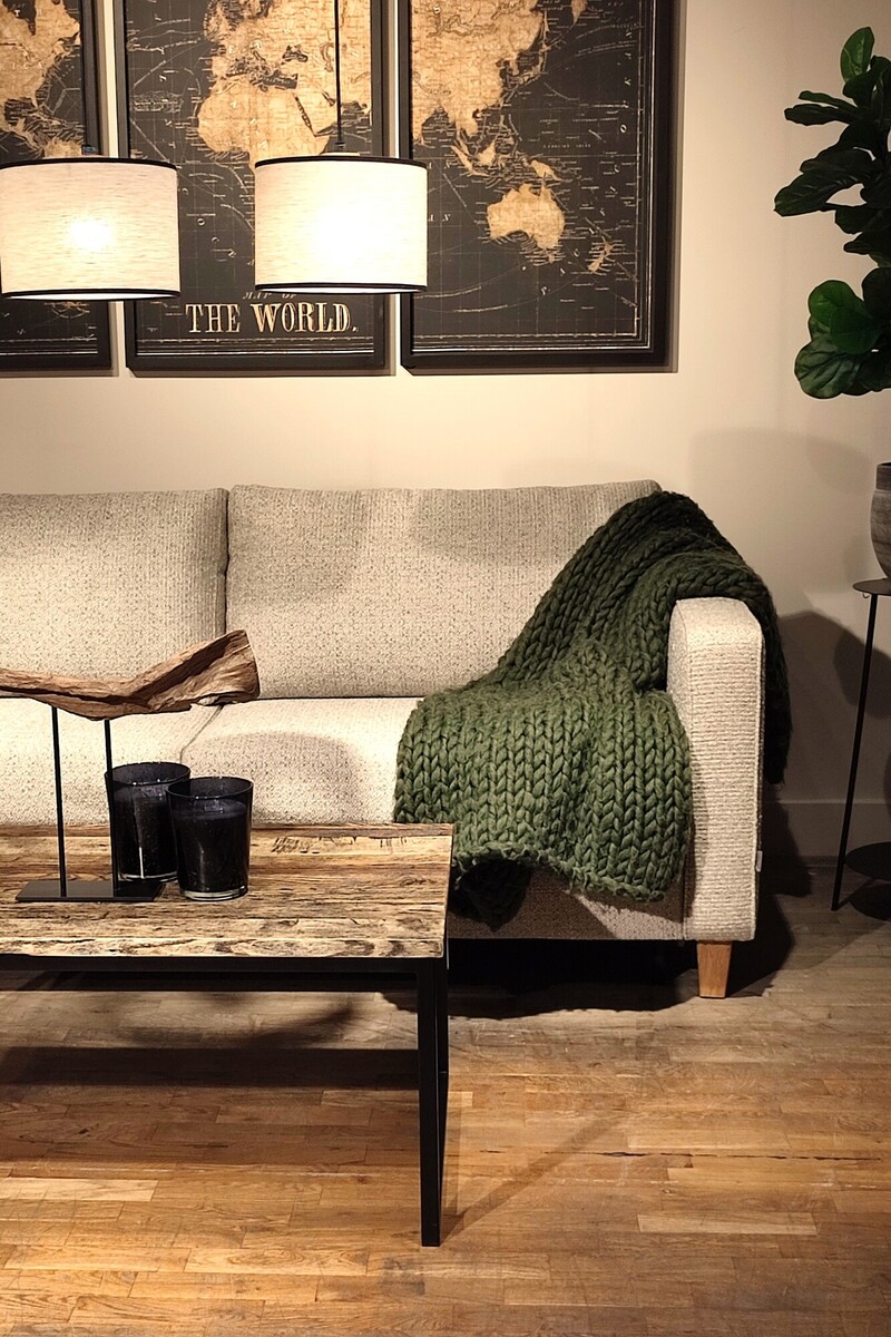 Sofa na drewnianych nóżkach, jasna sofa Esta Mti Furninova, zielony pled, duża roślina do salonu, naturalne dodatki