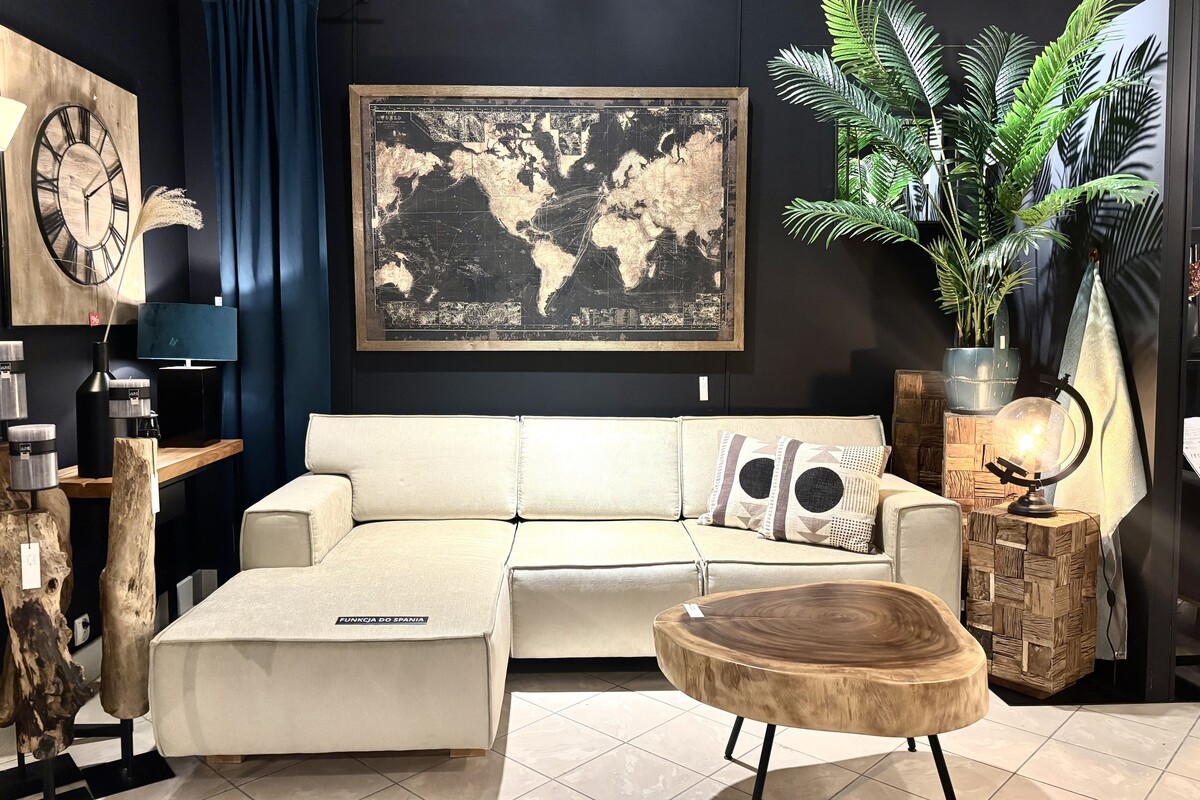 Beżowy narożnik do spania, czarna ściana w salonie, Trivento Mti Furninova. Obraz mapa świata, ciekawy stolik kawowy. Sofa z szezlongiem rozkładana