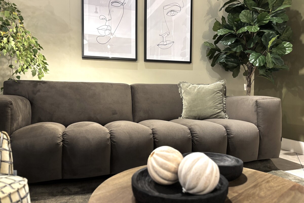Czekoladowa sofa Vesta Quilt na oliwkowej ścianie. Trzyosobowa pikowana sofa welurowa w kolorze mocha mousse. Oliwkowe ściany w salonie i zielony dywan. 