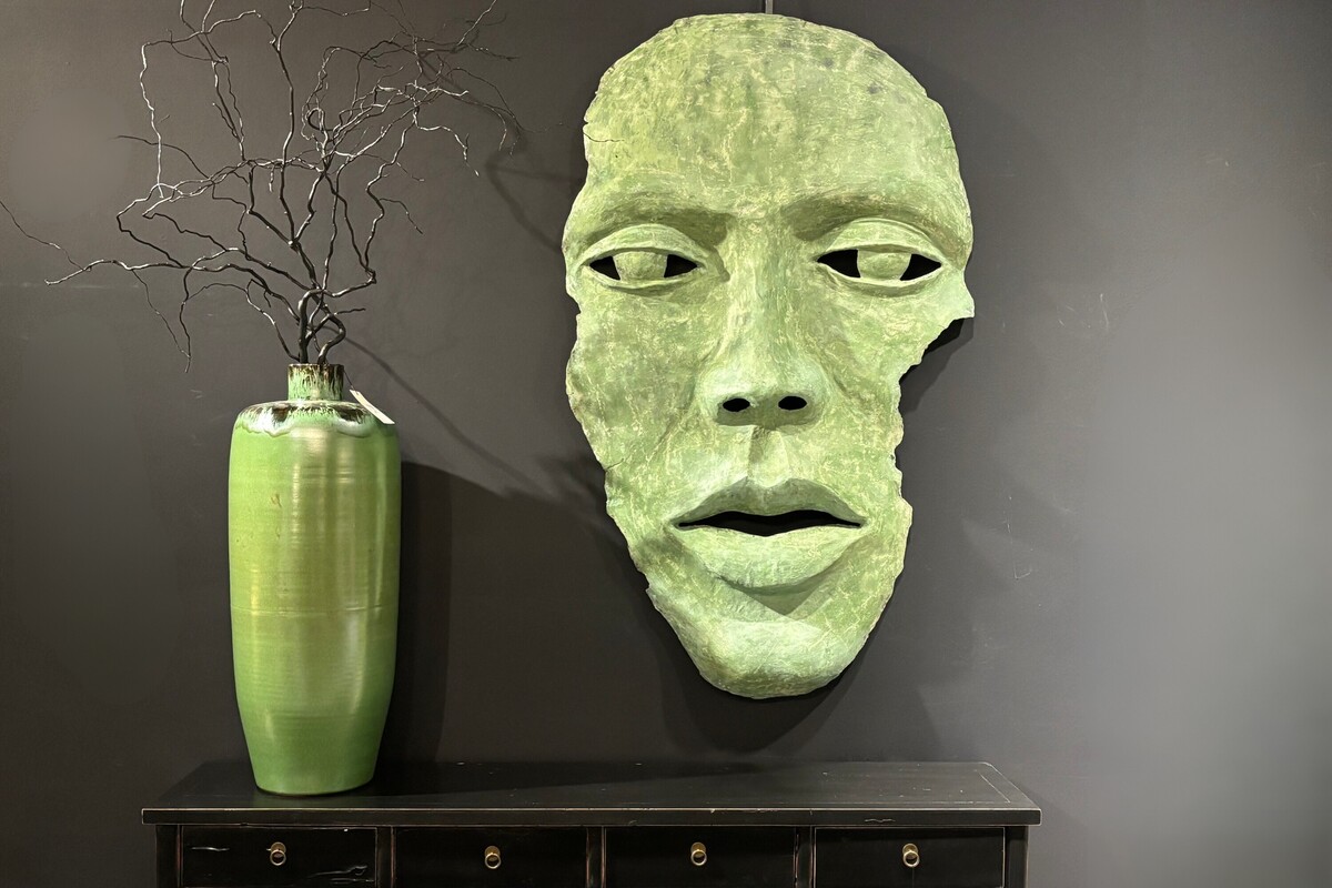 Rzeźba twarz, zielona maska twarz na czarnej ścianie. Płaskorzeźba w kolorze zielonym, czarna konsola z szufladami. Oryginalna duża płaskorzeźba ścienna. Konsola z szufladami.