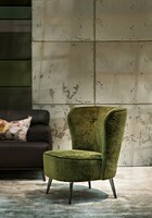 Zielony, welurowy fotel z metalowymi nogami pięknie współgra industrialnym wnętrzem