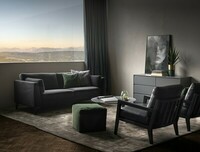 Fotel Karetta, czarna rama , obicie naturalna skóra licowa, w tle sofa Avignon - ciemny velur, zielony puf praline, poduszki dekoracyjne, beżowy dywan,  grafitowa komoda, nowoczesne stylowe wnętrze, ciekawa grafika