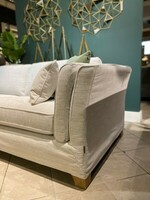 Jasno beżowa kanapa z luźnym pokrowcem, zgrabna kanapa do salonu, mała sofa tapicerowana 