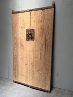 Duże drewniane drzwi z ręcznie wykonanymi okuciami, ciekawy pomysł na zagłówek do łóżka. 